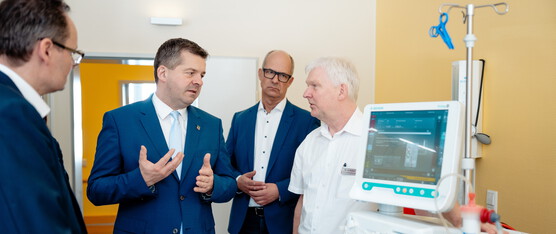 Sven Schulze im Gespräch mit anderen Personen, ein medizinisches Gerät ist im Vordergrund zu sehen